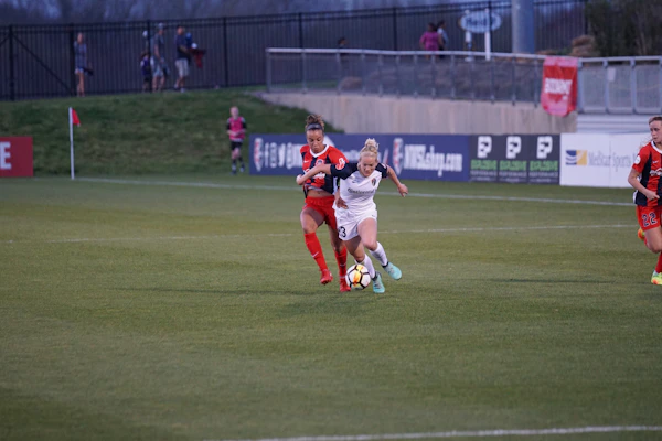 Action shot of a female player wearing a stylish black and gold jersey sprinting on the field.