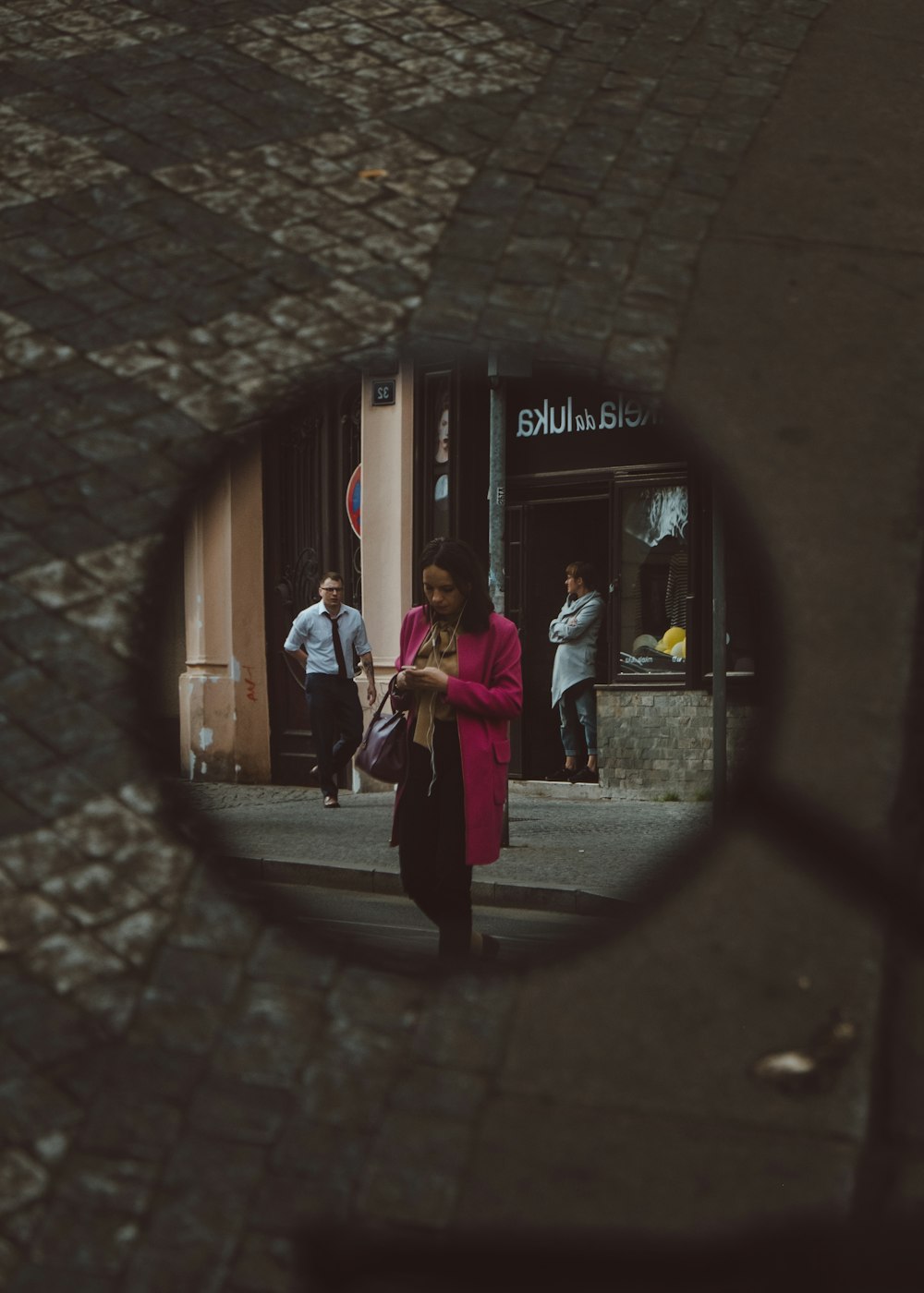 mirror showing woman wearing pink coat walking on street