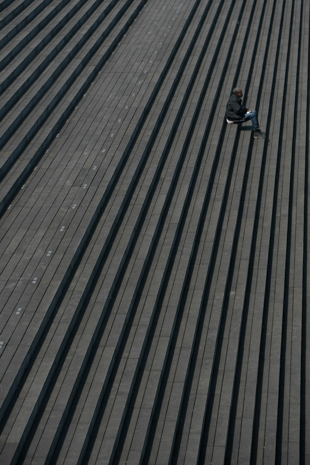 man in black jacket sitting on gray stair