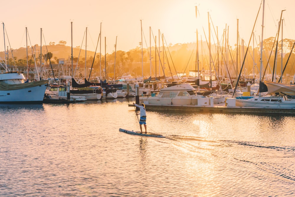 person riding paddle board beside yacht