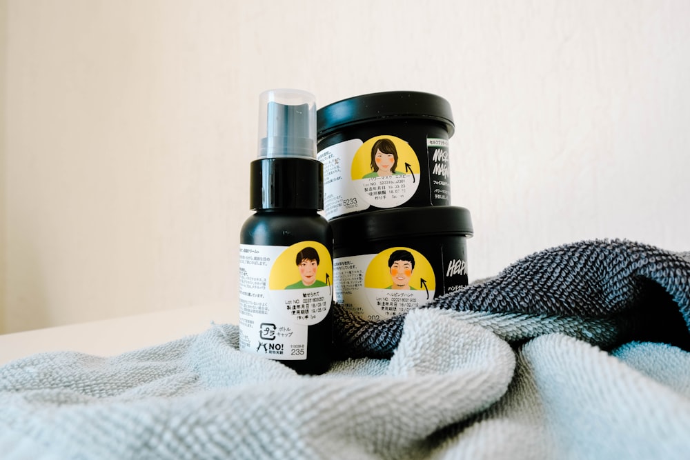 three black and white labeled hair products on white and grey textile