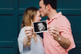man kissing woman's forehead white holding ultrasound photo