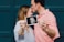 man kissing woman's forehead white holding ultrasound photo