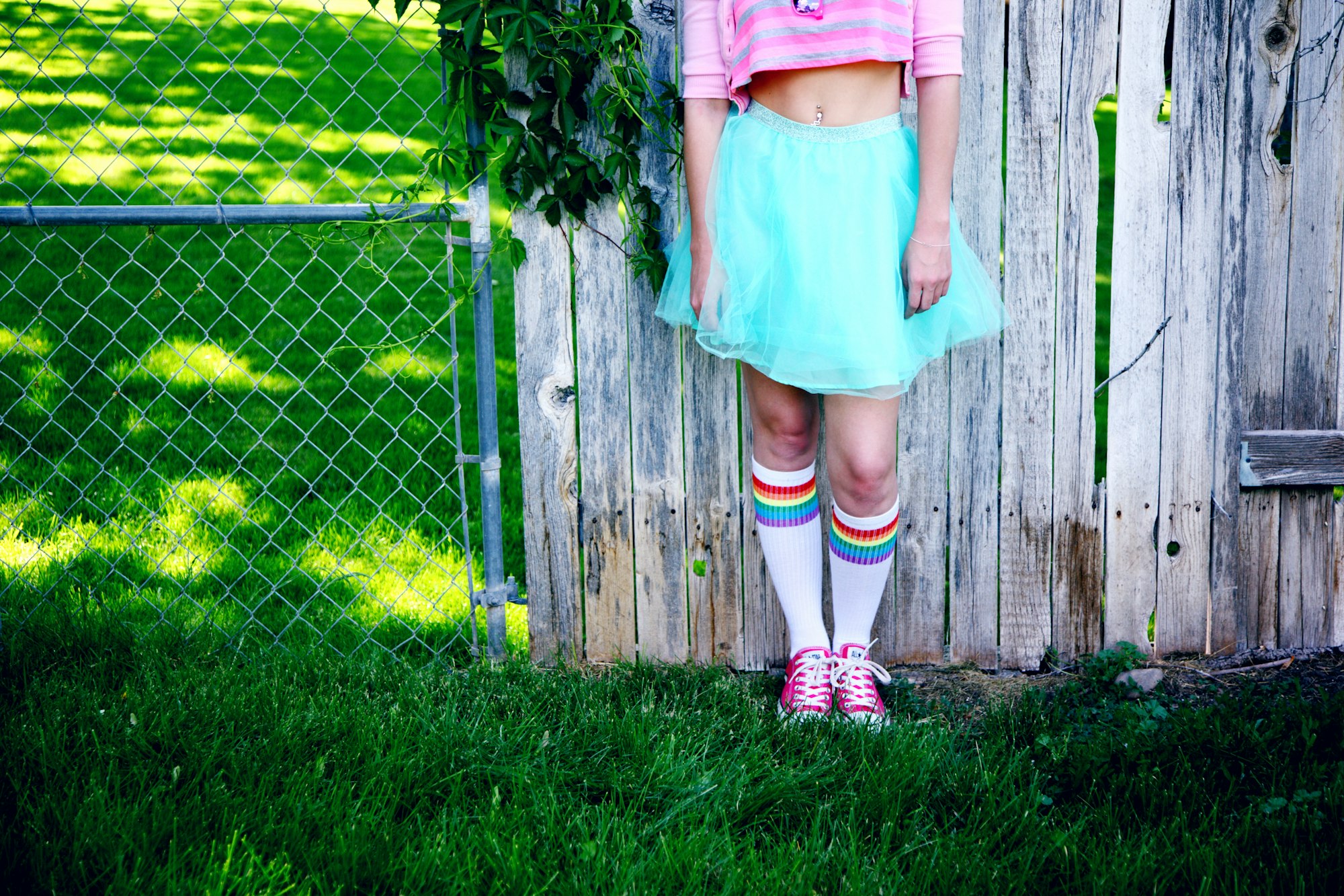 Portrait of a teenage girl standing against a wooden fence wearing a playful outfit for Gay Pride 2018.