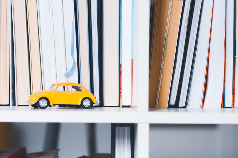 yellow Volkswagen beetle toy on wooden shelf