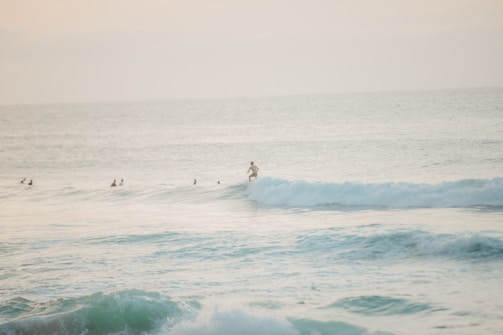 A beginner surfer catching their first wave under the guidance of a friendly instructor at Legian Beach.