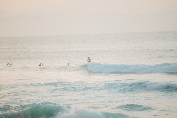An instructor helping a student balance on the surfboard during a lesson in the gentle waves.