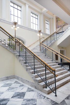 gray and white staircase near window with brass holders