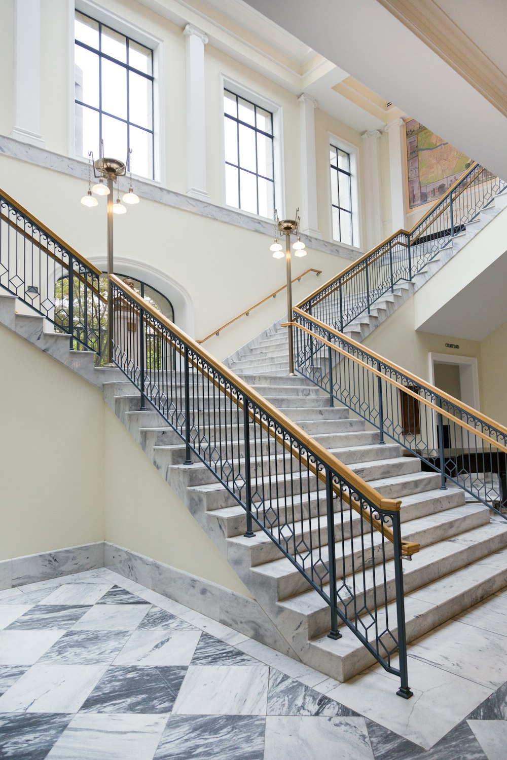 gray and white staircase near window with brass holders