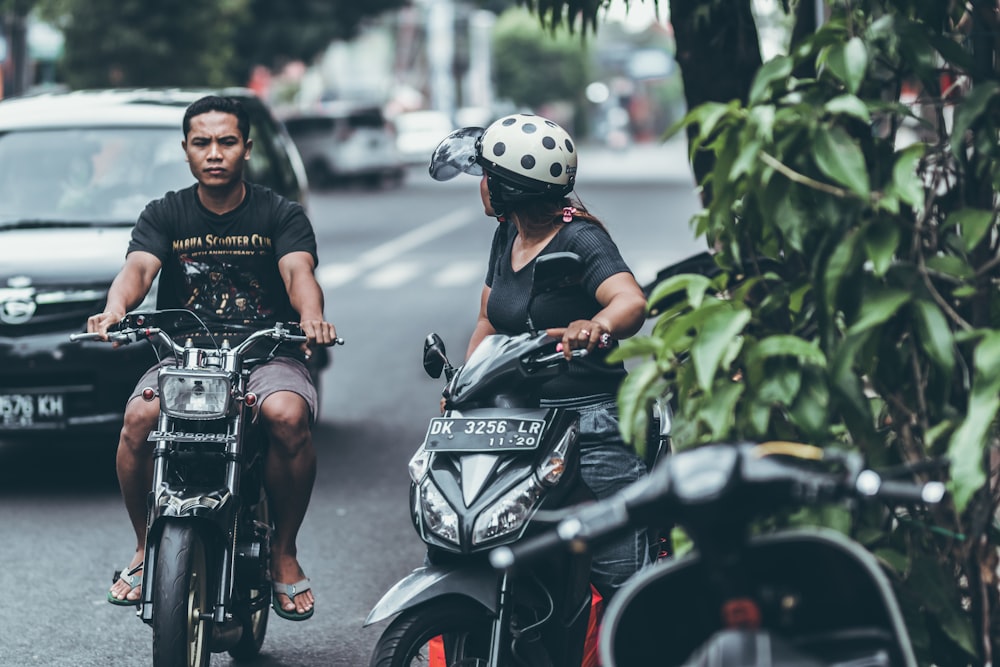 man and woman riding on motorcycle at daytime