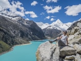 girl sitting on rock near body of water at daytime