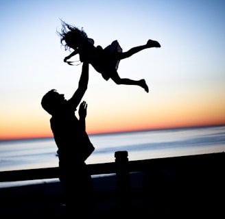 silhouette of man throwing girl in air