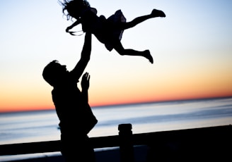 silhouette of man throwing girl in air