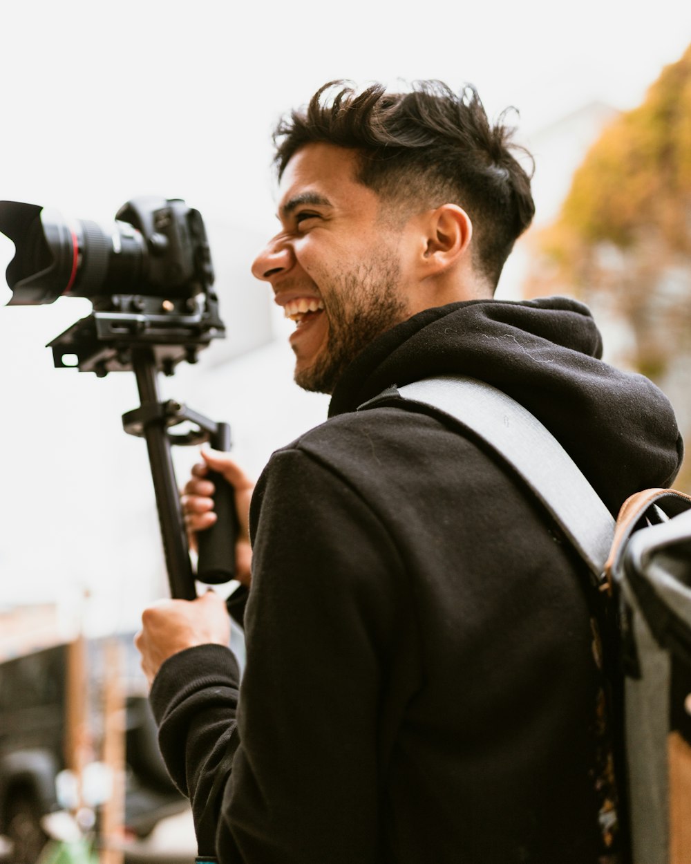 man smiling while holding DSLR camera
