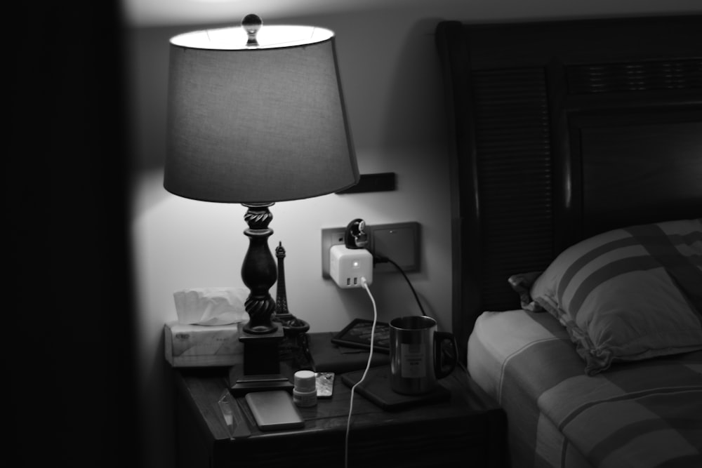 grayscale photo of table lamp near bead