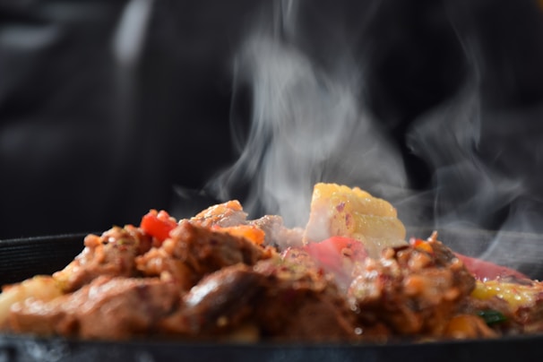 A close-up of sizzling pork sisig served on a hot plate.