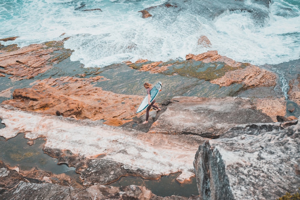 Persona sosteniendo una tabla de surf en la orilla del mar