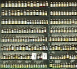 Rows of glass jars filled with vibrant herbal powders on wooden shelves.