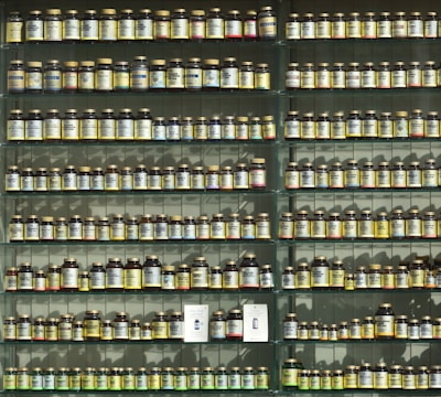 Rows of glass jars filled with vibrant herbal powders on wooden shelves.