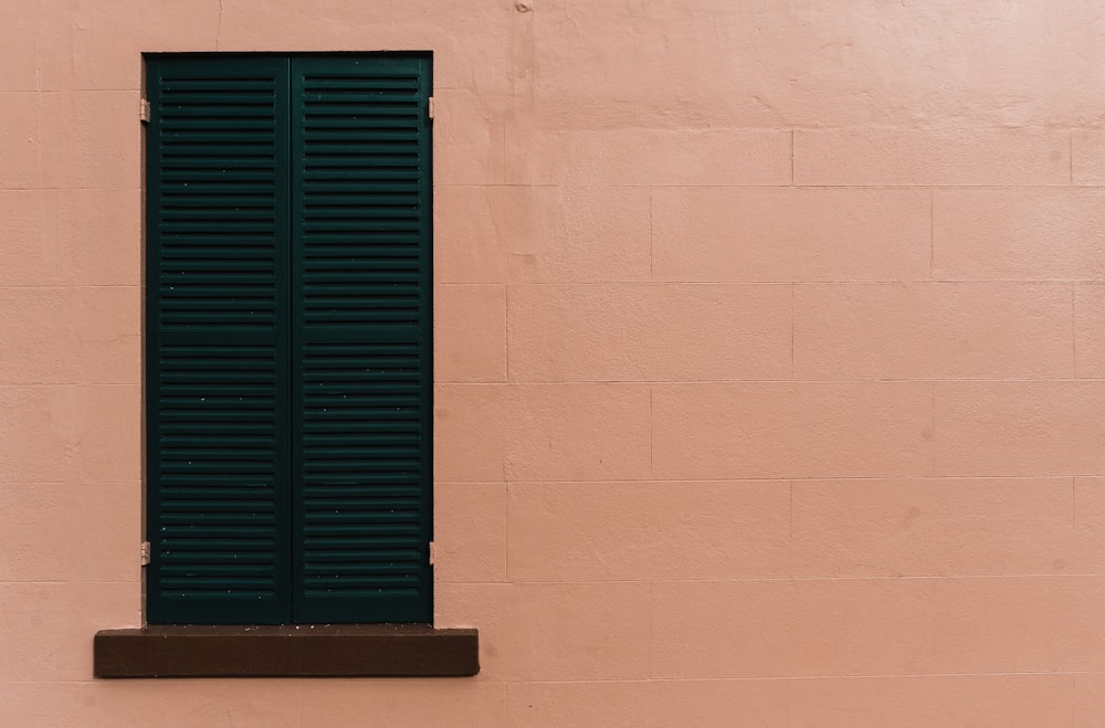 brown wooden building with green louvered window