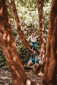 girl and boy playing on tree in the forest