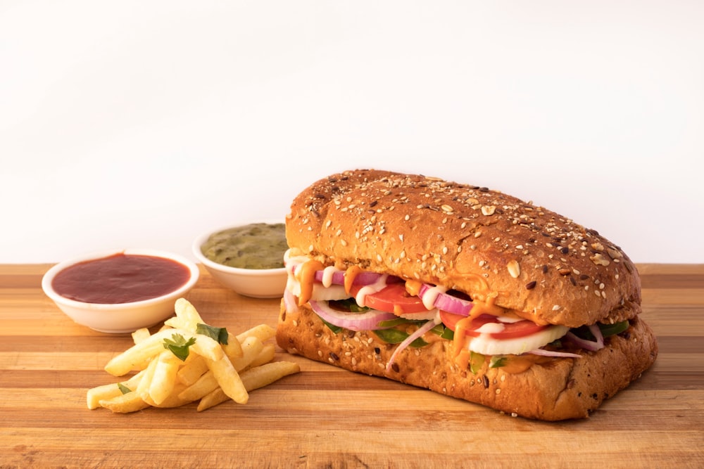 burger sandwich and potato fries on brown wooden surface