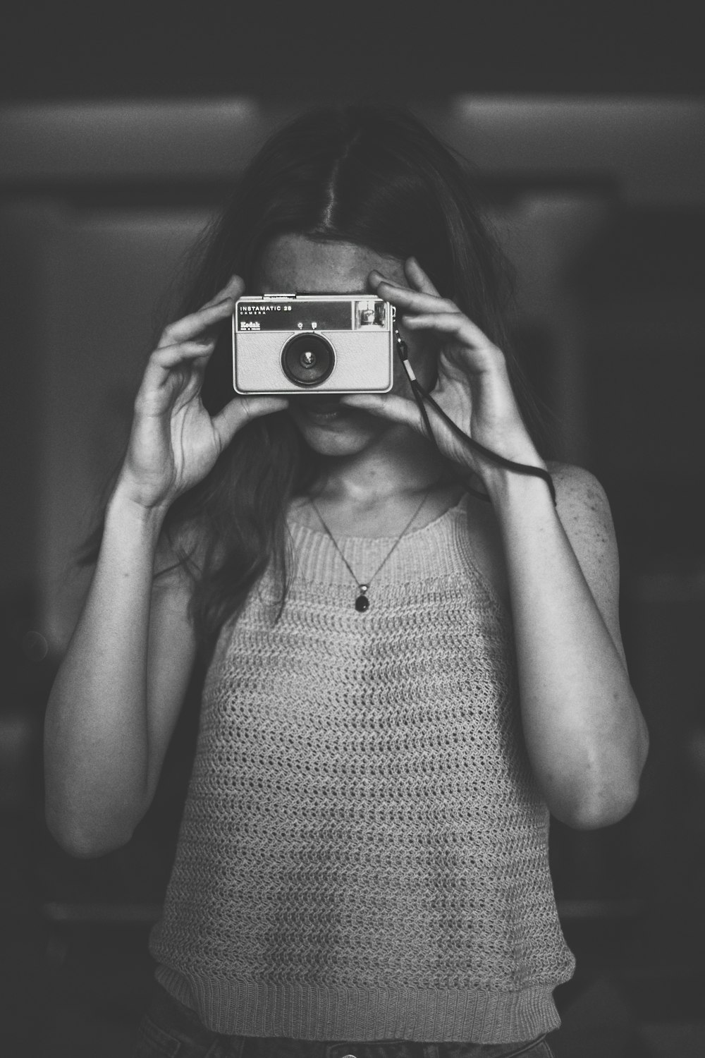 カメラを使用したスパゲッティストラップトップの女性のグレースケール写真