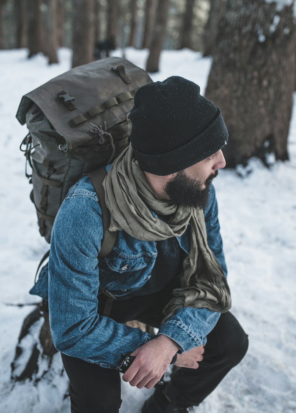 man sitting on snow near trees