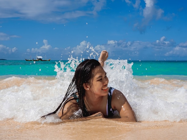A joyful traveler standing on a pristine beach with turquoise waves gently lapping the shore.