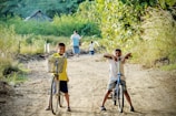 two boy riding on bicycle on dirt road