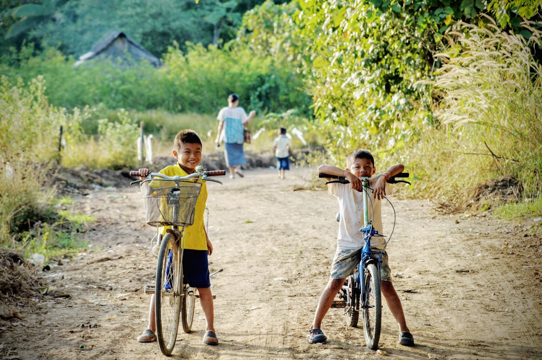 two boy riding on bicycle on dirt road