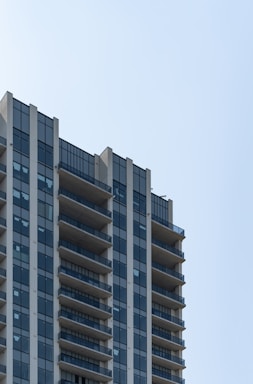 Newly built residential tower with glass windows and balconies.