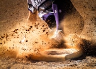 Close-up of a player sliding into base wearing custom red and white softball pants and jersey.