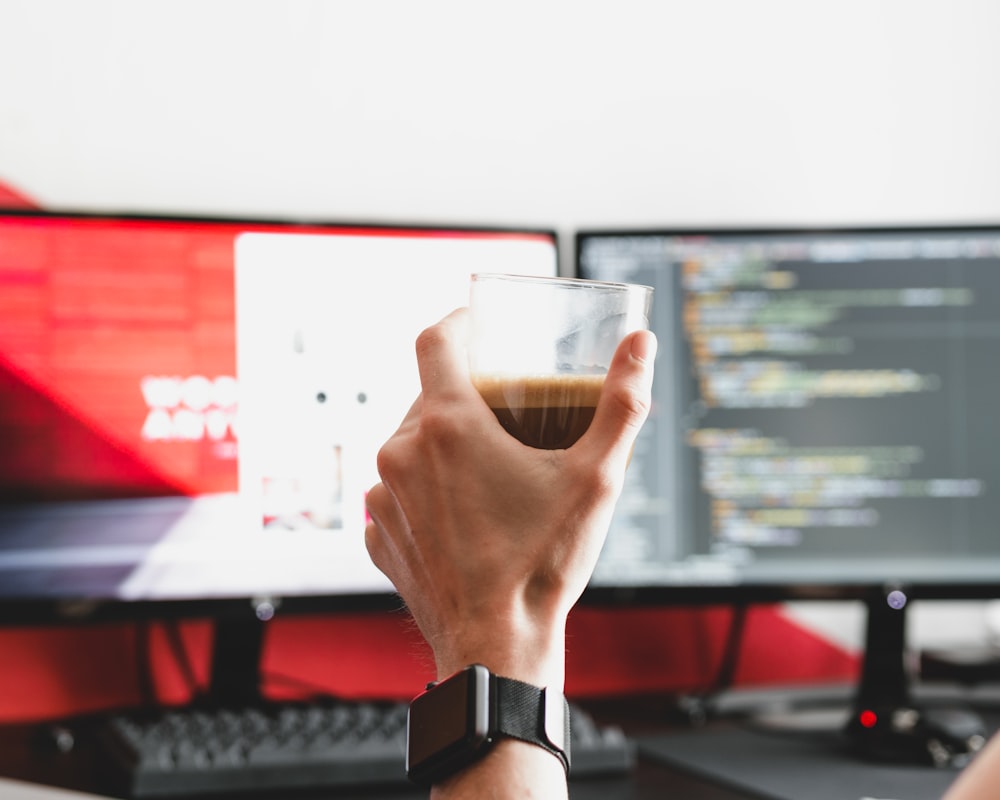 Persona sosteniendo un vaso transparente con bebida en su interior