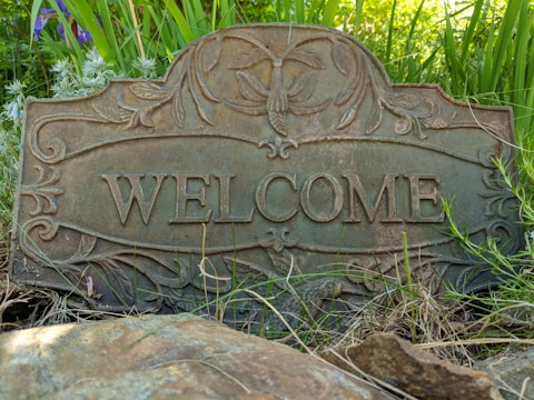 A charming outdoor scene featuring a rustic welcome sign surrounded by yard decorations