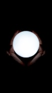 Close-up of hands gently holding a glowing light orb