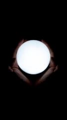 Hands gently hovering over a glowing orb symbolizing energy healing and spiritual connection.