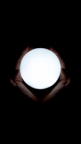A calm hand gently hovering over a glowing orb of soft energy light, symbolizing the gentle touch of energy healing.