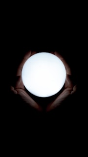 A close-up of hands holding a glowing orb symbolizing spiritual insight and life path