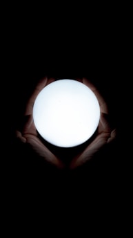 Hands gently hovering over a glowing orb symbolizing energy healing and spiritual connection.
