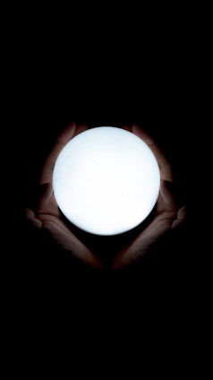A close-up of hands holding a glowing orb symbolizing spiritual evolution and healing.