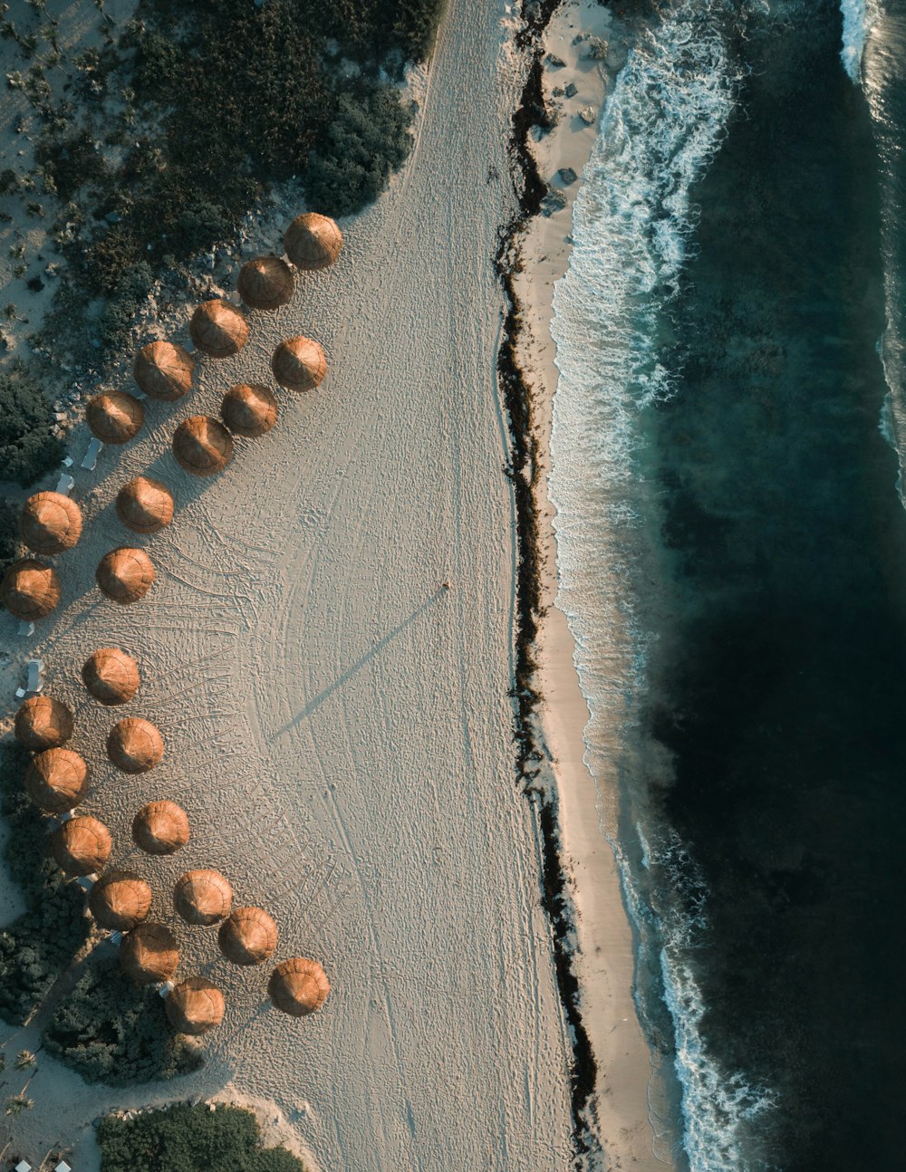 낮에 해변에 있는 갈색 오두막의 항공 사진