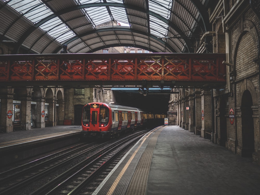 red train traveling inside a train station