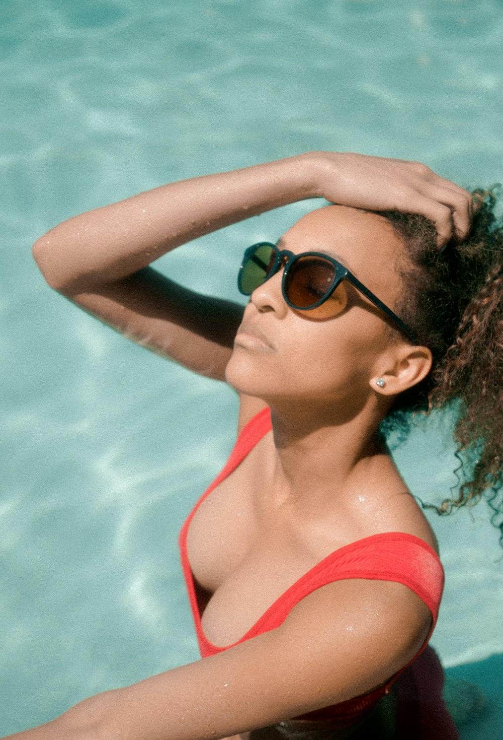 woman holding her hair while dipped in pool