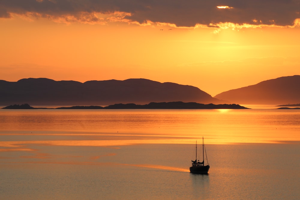 fishing boat at the ocean near island during sunset