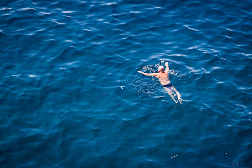 man swimming on body of water