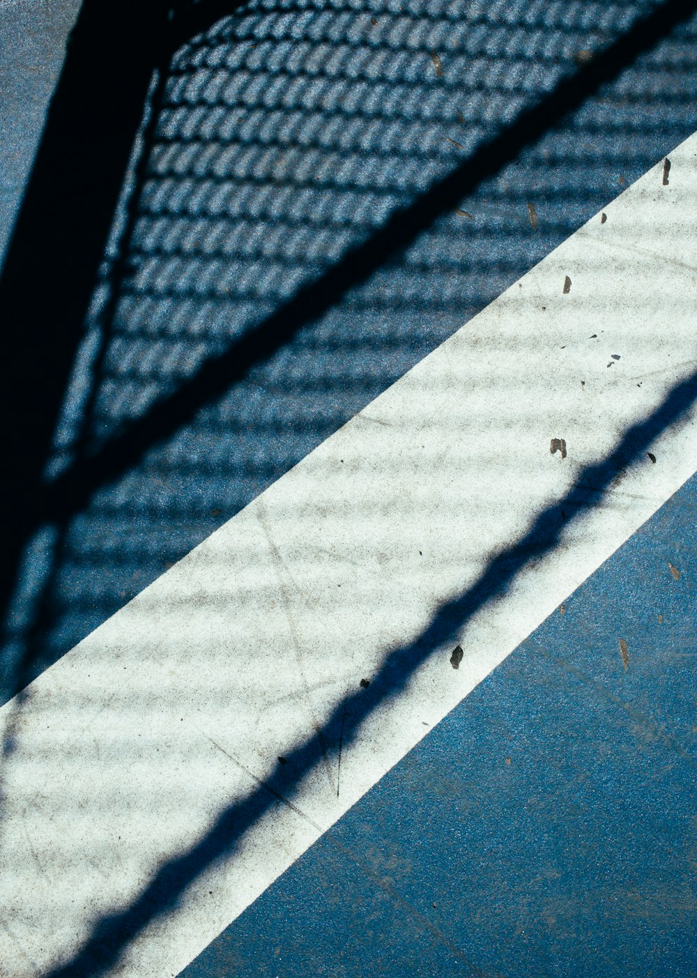 コンクリート舗装に映し出されたフェンスの影