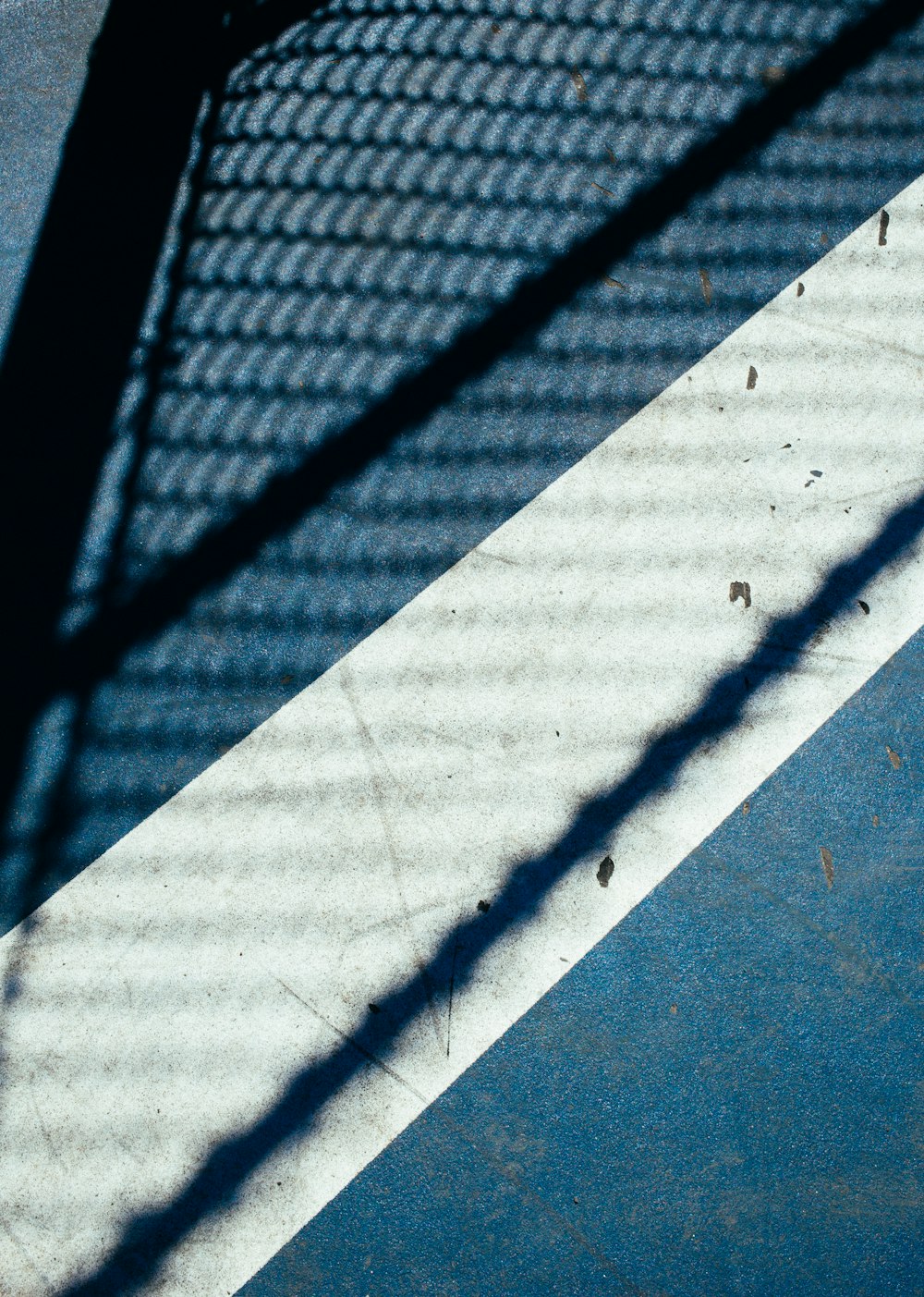 shadow of fence casted on concrete pavement