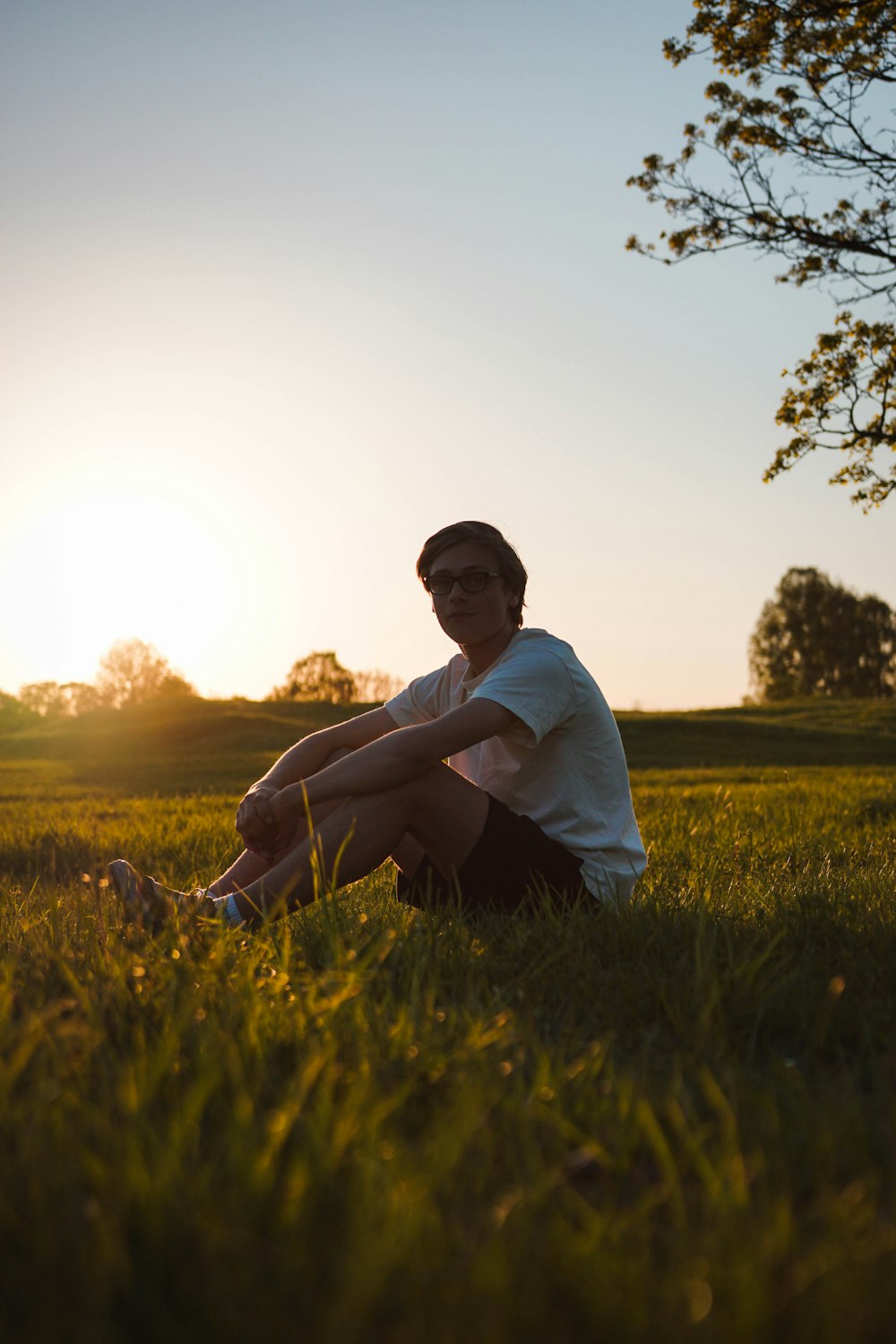 man sitting on grass field during sunset