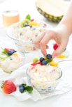 person holding blueberry fruit with hands on top of fruit salad
